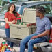 A man and woman standing in the back of a truck with a CaterGator outdoor cooler.