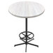A round white Holland Bar Stool outdoor bar table with a white ash wood laminate top and a black metal foot rest base.