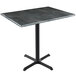 A Holland Bar Stool black steel table with wood laminate top on a black steel cross base.