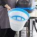 A man using a Lavex stainless steel wet/dry vacuum to clean a blue and white bucket.