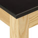 A close up of a black table with a wood grain phenolic top.