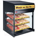 A Hatco countertop food warmer with shelves of donuts inside.