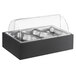 A wooden display stand with black and silver Vollrath food pans and a clear roll top cover.