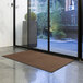 A brown Lavex Olefin entrance mat rolled out on a floor.