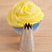 A cupcake with yellow frosting piped with an Ateco metal open star piping tip.