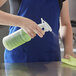 A person in a blue apron using Bacoff ready-to-use sanitizer spray on a counter.
