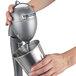 A hand holding a silver Hamilton Beach drink mixer with a cup.