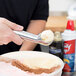 A person using a Zeroll aluminum ice cream scoop to scoop ice cream.