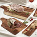 A group of Solia cardboard bistro boards with meat and vegetables on them.