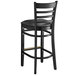 A Lancaster Table & Seating black wood ladder back bar stool with a black vinyl cushion.