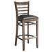 A Lancaster Table & Seating wooden ladder back bar stool with a black vinyl seat