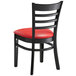 A Lancaster Table & Seating black wood ladder back chair with red vinyl seat.
