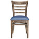 A Lancaster Table & Seating wooden ladder back chair with navy blue vinyl cushion.