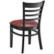 A black Lancaster Table & Seating wood ladder back chair with a burgundy vinyl seat