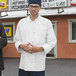 Two men standing outside a restaurant, one wearing an Uncommon Chef white long sleeve coat with a black knot.