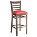 A Lancaster Table & Seating wooden bar stool with red vinyl seat.
