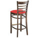 A Lancaster Table & Seating wood bar stool with red vinyl seat.