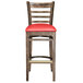 A Lancaster Table & Seating wood ladder back bar stool with red vinyl seat.