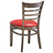 A Lancaster Table & Seating wooden ladder back chair with a red vinyl seat.