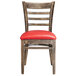 A Lancaster Table & Seating wooden restaurant chair with a red vinyl seat and ladder back.