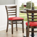 A table with Lancaster Table & Seating Vintage Finish Wood Ladder Back Chairs with Red Vinyl Seats and wine glasses.