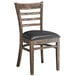 A Lancaster Table & Seating wooden ladder back chair with a black vinyl seat.
