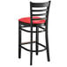 A Lancaster Table & Seating black wood ladder back bar stool with a red vinyl seat
