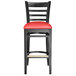 A Lancaster Table & Seating black wood bar stool with red vinyl seat.