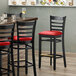 A Lancaster Table & Seating black wood ladder back bar stool with a red vinyl seat