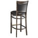 A Lancaster Table & Seating Sofia wood bar stool with a black vinyl seat.
