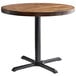 A Lancaster Table & Seating round wooden table with a black base.