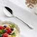 An Acopa stainless steel spoon next to a bowl of fruit and yogurt.