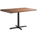 A Lancaster Table & Seating rectangular wood butcher block table with a vintage finish and a black cast iron base.