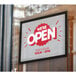An E-Z Up rectangle window decal with white text that says "We Are Open" on a glass window.