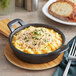 A Tablecraft mini cast iron round casserole dish filled with macaroni and cheese.