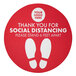 A red E-Z Up circle floor decal with white text and footprints for social distancing.