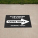 A black square floor decal with white text reading "One Way" and an arrow pointing forward.