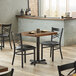 A Lancaster Table & Seating rectangular wood butcher block table with 2 black cross back chairs.