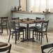 A Lancaster Table & Seating wood butcher block table with black chairs in a restaurant.