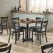 A Lancaster Table & Seating wood butcher block table with black chairs around it in a restaurant.