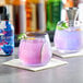 Two glasses of purple Wild Hibiscus floral drinks with lime slices on a bar counter.