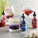 A table with a variety of drinks, including a glass of Wild Hibiscus Floral Extract.