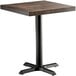 A Lancaster Table & Seating square wood table with a black base.