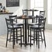 A Lancaster Table & Seating round butcher block bar table with chairs around it.