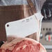 A person using a Choice stainless steel cleaver to cut meat on a counter.