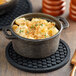 A bowl of macaroni and cheese on a Valor black silicone trivet on a wooden table.