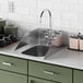 A Waterloo stainless steel drop-in sink with side splashes in a green kitchen with white tile.