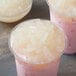 A cup of pink milk with Bossen Lychee Jelly Topping on white food.