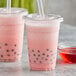 Two plastic cups with straws and Bossen rose pink drinks.