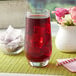 A glass of Bossen Rose Garden fruit tea with ice cubes on a table with flowers.